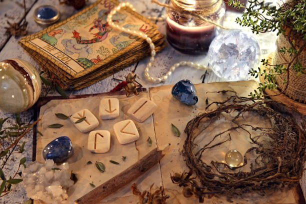 istock Open diary book with runes, dried herbs and tarot cards on table 1077895558