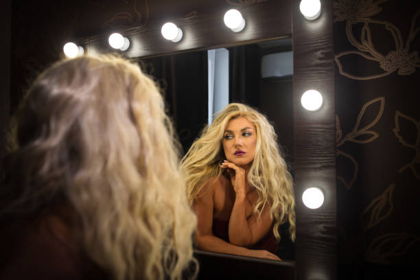 istock Young woman looking at himself in mirror in dressing room 1077895700