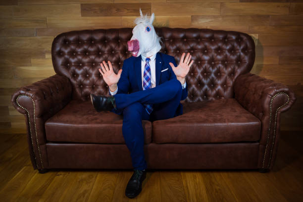 istock Funny unicorn in elegant suit siting on sofa like a boss 1077895728
