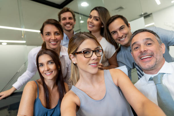 istock Latin american business group at the office having fun taking a selfie facing camera smiling 1077900688