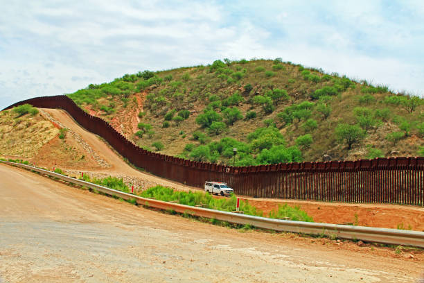 Border Fence Separating the US from Mexico Near Nogales, Arizona Border Fence beside a road near Nogales, Arizona separating the United States from Mexico with border patrol vehicle. nogales arizona stock pictures, royalty-free photos & images