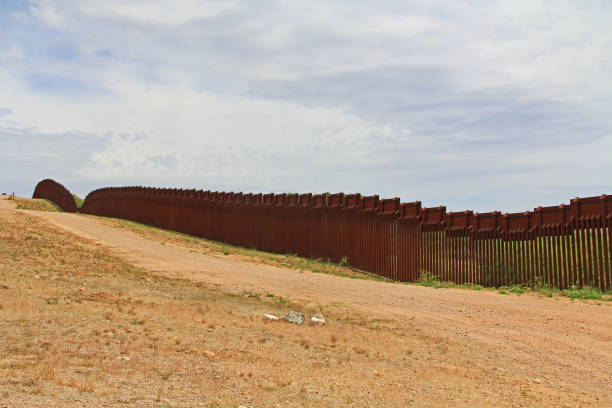 Border Fence Separating the US from Mexico Near Nogales, Arizona Border Fence beside a road near Nogales, Arizona separating the United States from Mexico. nogales arizona stock pictures, royalty-free photos & images