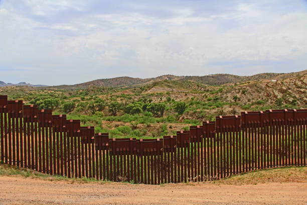 Border Fence Separating the US from Mexico Near Nogales, Arizona Border Fence beside a road near Nogales, Arizona separating the United States from Mexico. nogales arizona stock pictures, royalty-free photos & images
