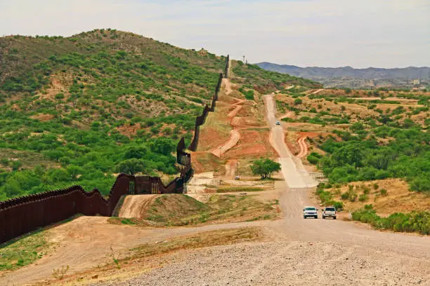 Border Fence beside a road near Nogales, Arizona separating the United States from Mexico with border patrol vehicle.