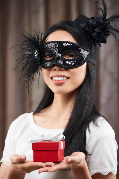 Cute young girl, posing in a homemade Photo Booth with props and party hat. She is wearing star shaped glasses on a stick and looking at the camera.