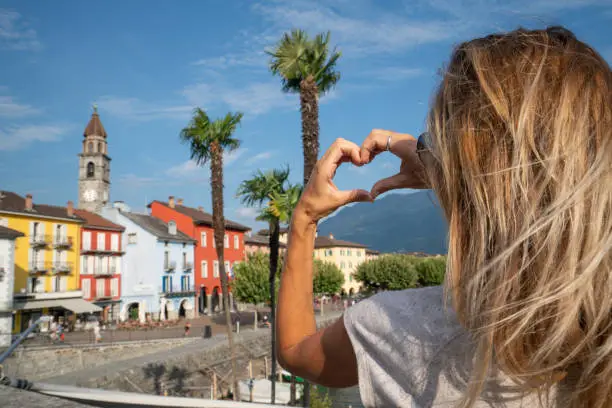 Photo of Young woman loving Swiss village in Ascona, Ticino, Switzerland making heart shape frame with hands