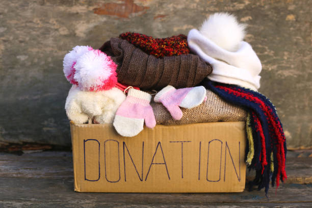 scatola di donazione con caldi vestiti invernali su vecchio sfondo di legno. - coat foto e immagini stock