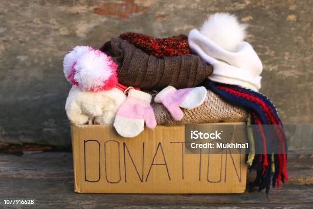 Donation Box With Warm Winter Clothes On Old Wooden Background Stock Photo - Download Image Now