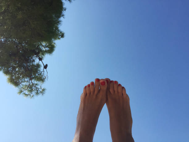 istock Girls feet on the beach, on sky background 1077920802