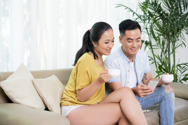 istock Content couple with coffee and phone on couch 1077930674