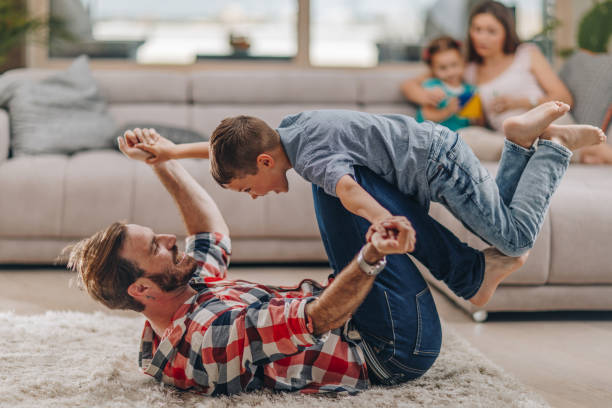 istock Playful father and son having fun on the carpet at home. 1077938784
