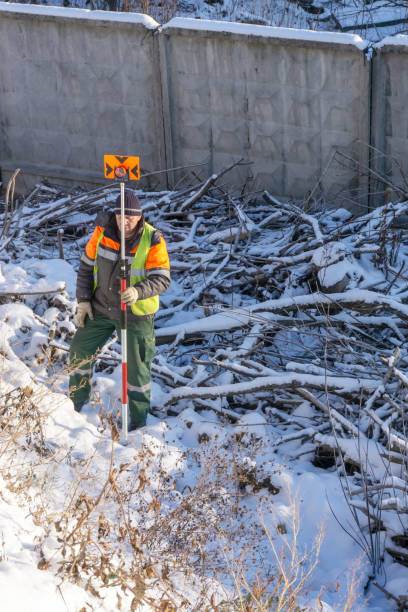istock Surveyor's assistant holds a measuring prism for cadastral work 1077940676