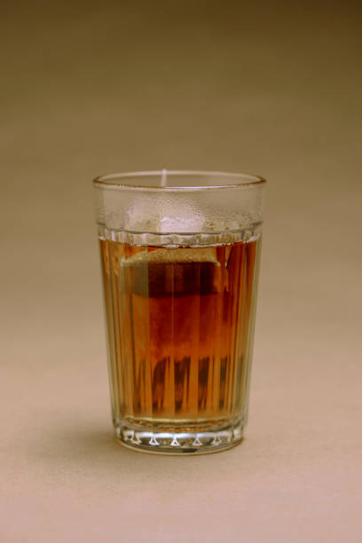istock Glass with black tea on a brown background 1077942528
