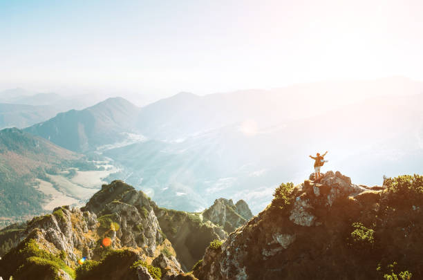 istock Mountain hiker with backpack tiny figurine stands on hiest mountain peak with beautiful panorama. Healthy trekking time spending concept. 1077942654