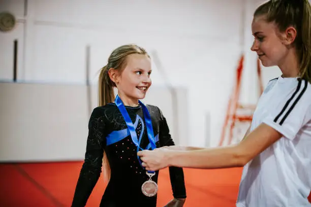 Photo of Coach giving a silver medal to a young gymnast