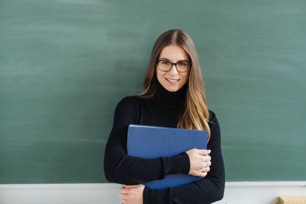 istock Young smiling female teacher against blackboard 1077973350