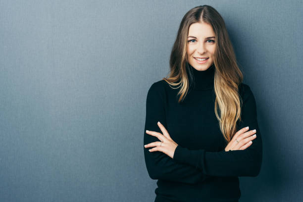istock Young smiling woman standing with arms crossed 1077974888