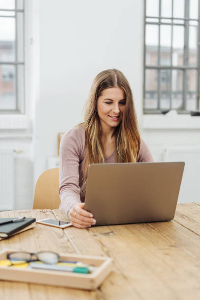 istock Young smiling woman working on laptop in office 1077975084