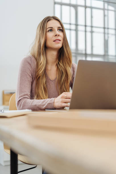 istock Young thoughtful woman working on laptop in office 1077975252