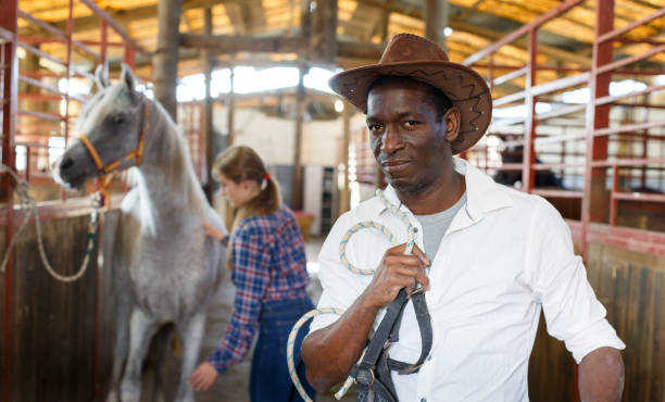 istock Afro man horse farm worker 1077978388