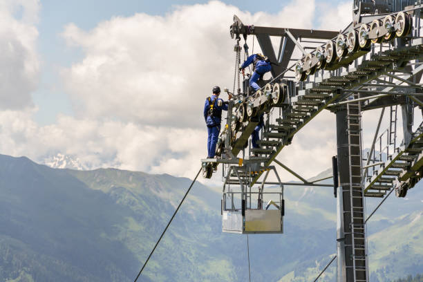 Saalbach-Hinterglemm, Austria - June 20, 2018: Two workers doing maintenance on cable car with Alps mountains in background, Schonleitenbahn on Wildenkarkogel on June 20, 2018 in Saalbach-Hinterglemm, Austria.