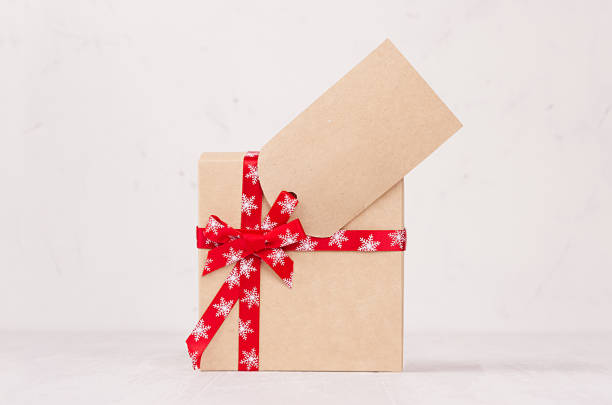 istock Modern gift box with red ribbon and blank label in elegance light white interior, copy space. 1077978748