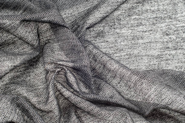 istock fabric gray black with white inserts metallic gold Thin white yarns are drawn on a black background, and thicker white yarns, twisted with a small amount of gold, create an almost spattered appearance 1077981114