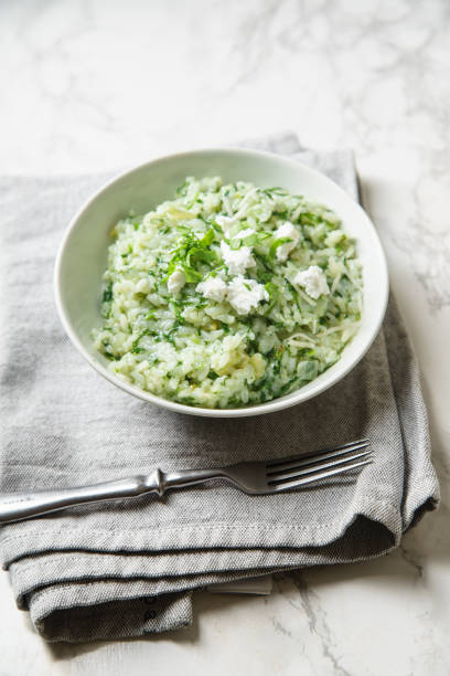 istock Spinach risotto with a glass of white wine on marble background 1077981708
