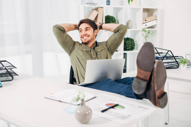 istock Smiling businessman relaxing on chair with hands on head 1077982462
