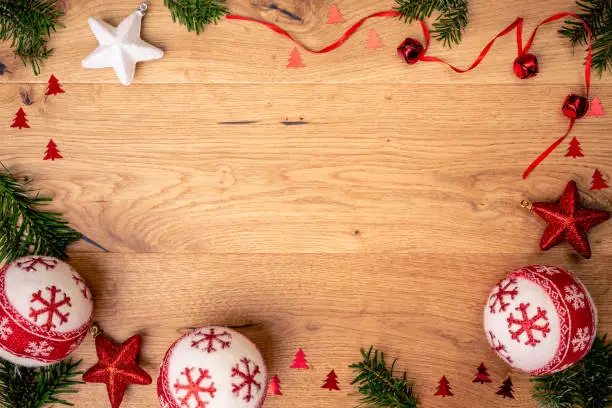 Christmas background with fir tree, red stars and christmass balls on brown wooden table. Top flat view with copy space.