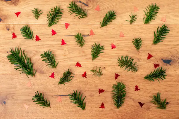 Christmas background with fir tree, red shiny fir trees on brown wooden table. Top flat view with copy space.