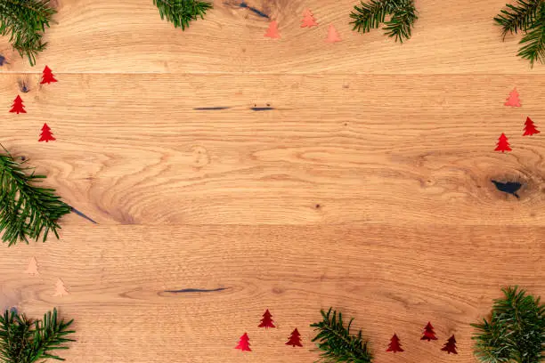 Christmas background with fir tree, red shiny trees on brown wooden table. Top flat view with copy space.