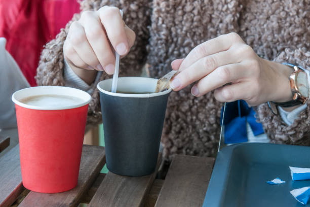istock Hands brew a tea bag holding a disposable paper cup and a plastic spoon. Selective focus 1077988688