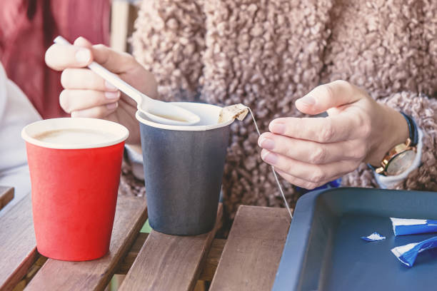istock Hands brew a tea bag holding a disposable paper cup and a plastic spoon. Selective focus 1077988698