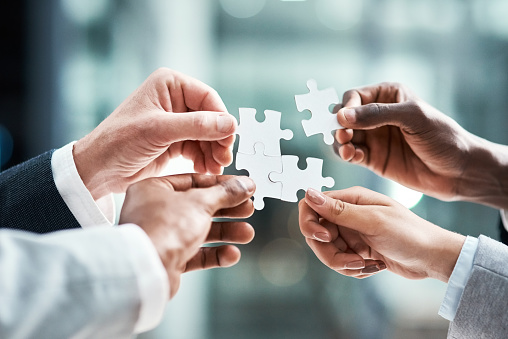 Concept of teamwork and partnership. Hands join puzzle pieces in the office. business people putting the jigsaws team together.Charity, volunteer. Unity, team business.