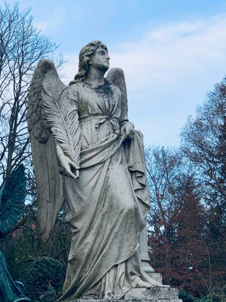 istock Angel holds a palm leaf, old tomb statue 1077988958