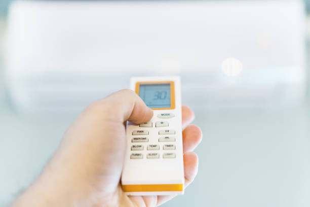 istock Hand holding remote control aimed at the air conditioner. 1077993112