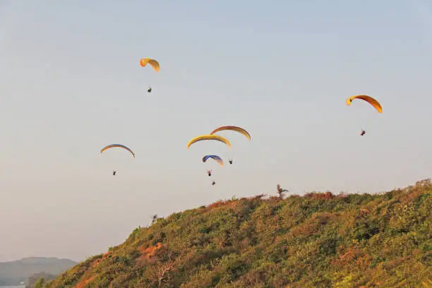 Photo of Paragliders against the blue sky. Bright paragliders fly in the