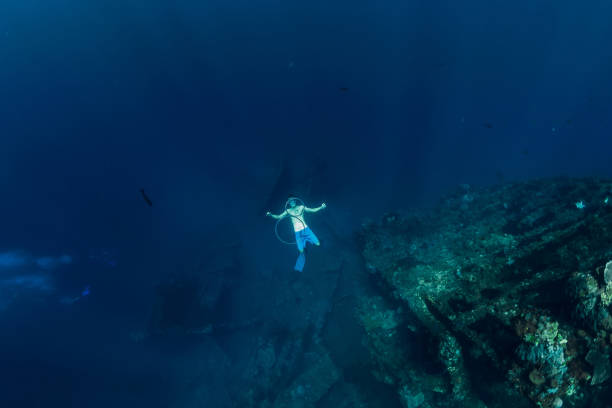 istock Free diver man in the depth make ring bubbles near shipwreck 1077999758