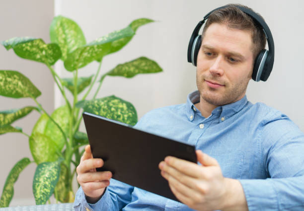 istock Man watching movie on tablet pc with wireless headphones. 1078001106