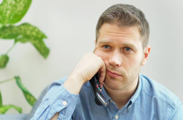 istock Handsome unshaved man watching boring TV show at home. 1078001144