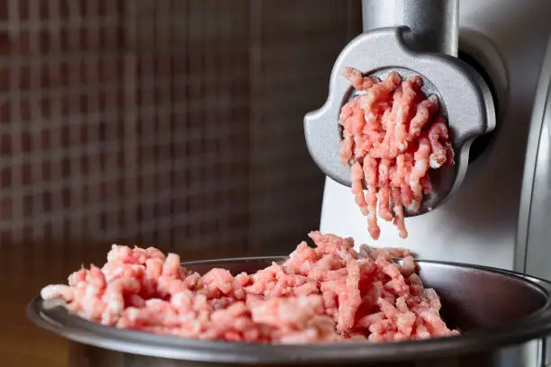 Minced meat coming out from modern electric grinder. Healthy fresh homemade minced meat. Place for copyspace.