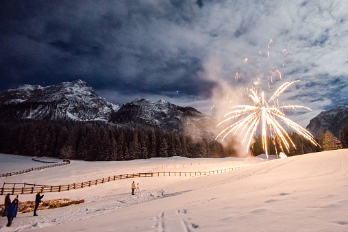 Firework for new year's eve in the mountains with some people whatching the explosions