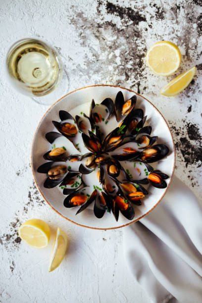 istock Boiled mussels and white wine on white stone table. 1078015964