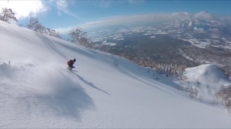 DRONE: Freestyle skier shredding the snow while riding in the scenic mountains.