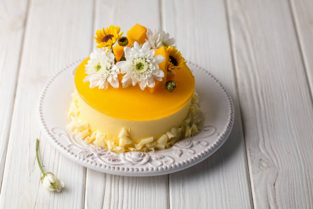 istock Glazed Mango cheesecake with flowers and fresh mango pieces on white wooden background 1078023048