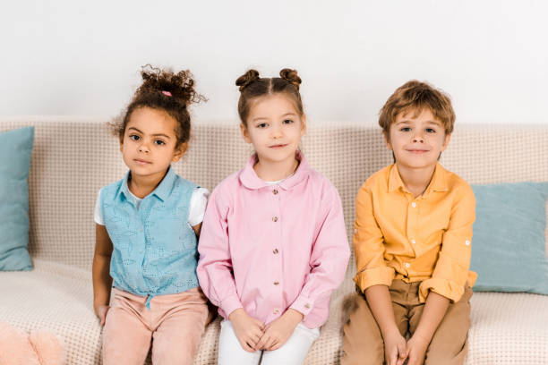 istock adorable multiethnic children sitting on sofa and smiling at camera 1078027580
