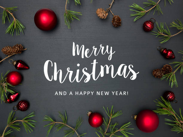 christmas background with lettering merry christmas, with frame with red baubles, green branches and other christmas items on blackboard