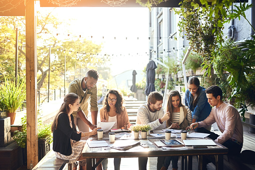 Cropped shot of a group of colleagues having a meeting outside at a cafe