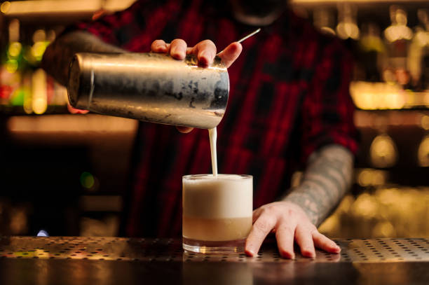 Bartender pouring a New York sour cocktail from the steel shaker